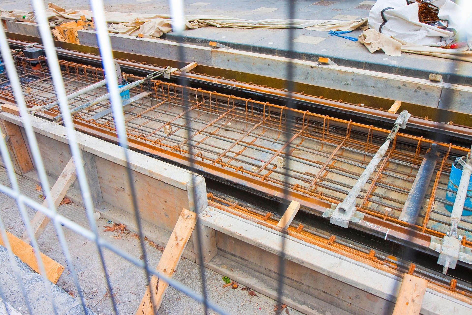 Construction site for repairing road and tram railways in the city seen from behind a metallic net